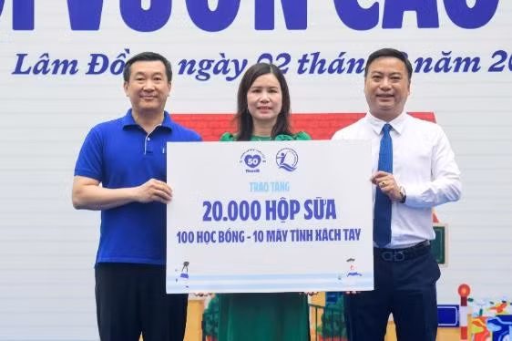 Đại diện Quỹ sữa Vươn cao Việt Nam, ông Đỗ Thanh Tuấn - Giám đốc Đối ngoại Vinamilk (trái) và ông Đinh Tiến Hải - Giám đốc Quỹ Bảo trợ Trẻ em Việt Nam - trao bảng tượng trưng các phần quà thiết thực cho đại diện Trường Tiểu học An Hiệp, xã Hiệp Thạnh (Ảnh: Hải An).