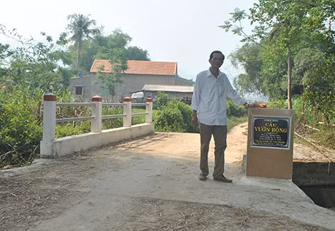 Ông Thành bên cây cầu do mình tích góp tiền bạc cả đời để xây dựng.