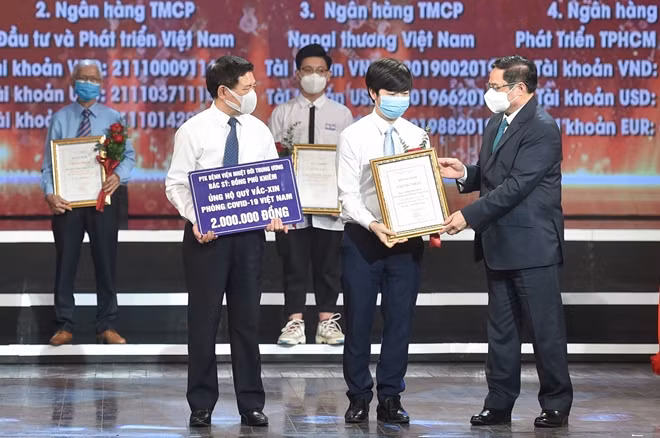 Thủ tướng Chính phủ Phạm Minh Chính trao chứng nhận, hoa cảm ơn Bác sĩ Đồng Phú Khiêm, Phó trưởng khoa điều trị tích cực - Bệnh viện Bệnh Nhiệt đới Trung ương. Ảnh VGP
