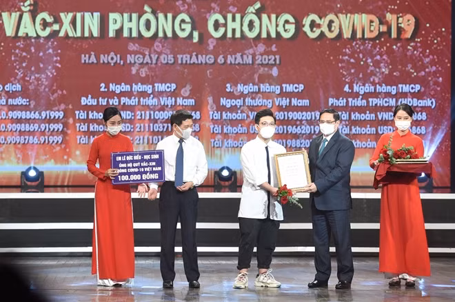 Thủ tướng Chính phủ Phạm Minh Chính trao chứng nhận, hoa cảm ơn em Lê Đức Hiếu, học sinh Trường Phạm Hồng Thái, Ba Đình, Hà Nội, 15 tuổi. Ảnh VGP