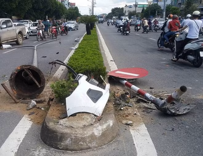 Cột đèn cao áp và biển báo giao thông gãy đổ sau khi bị taxi mất lái húc phải.