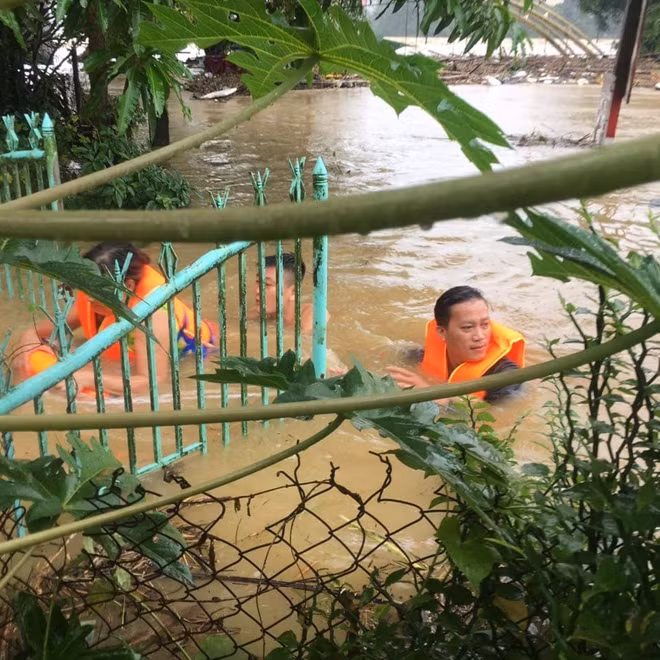 Lực lượng công an bơi vào nhà dân bị ngập lụt để ứng cứu, di dời người dân đến nơi an toàn.