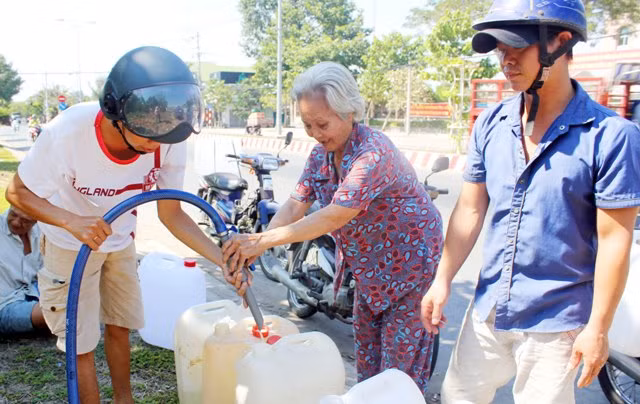 Bà Nguyễn Thị Huởn (SN 1944, ngụ ấp Phú Thành, xã Phú Hưng, TP Bến Tre, tỉnh Bến Tre) phát miễn phí nước ngọt cho người dân xung quanh.
