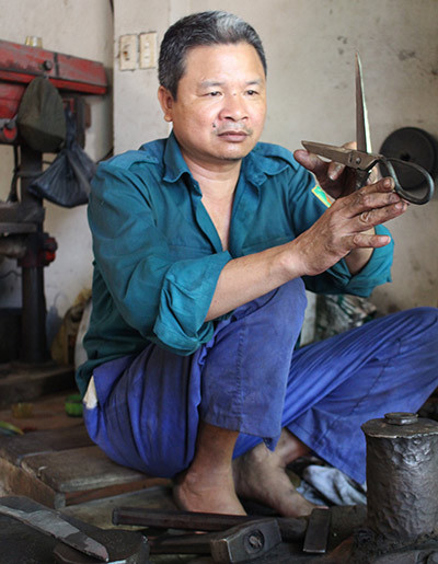 Thợ rèn Nguyễn Thế Thắng đang tỉ mỉ ngắm chỉnh kéo cắt may.