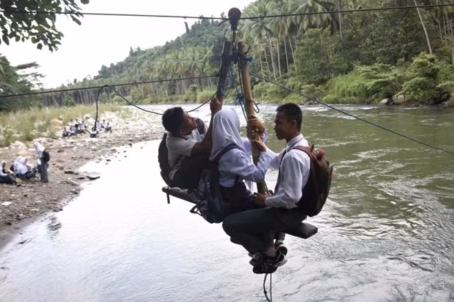 Ba học sinh băng qua con sông Ranteangin trên đường về nhà tại Kolaka Utara, Indonesia