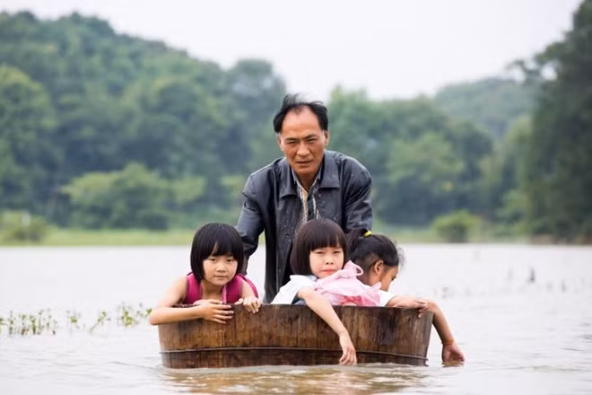 Một người đàn ông đẩy chiếc bồn gỗ lớn chở những cô bé trở về nhà trong khi khu vực này còn đang lụt trong nước tại Đỗ Xương, tỉnh Giang Tây, Trung Quốc