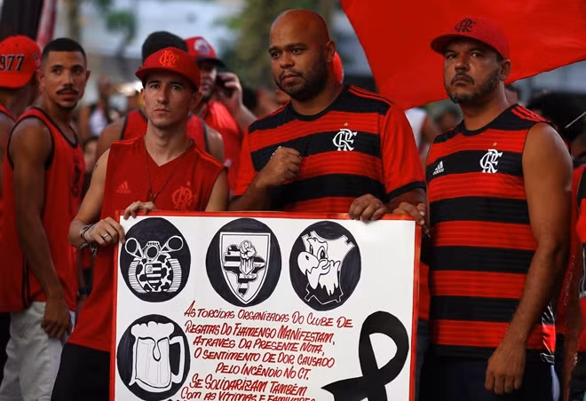 Người hâm mộ của câu lạc bộ với tấm bảng ghi thông điệp chia buồn tại Rio de Janeiro. Ảnh Reuters.