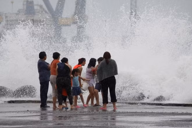 Bão gây ra sóng lớn nhưng một số người dân vẫn thản nhiên đùa nghịch