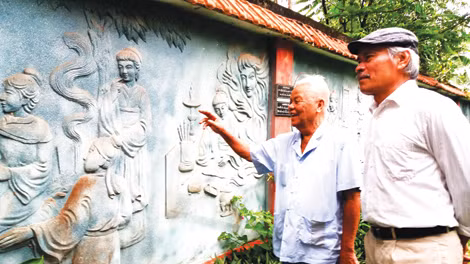 Ông Nguyễn Bá Khoát dẫn khách tham quan bức tường đắp phù điêu “Truyện Kiều”.