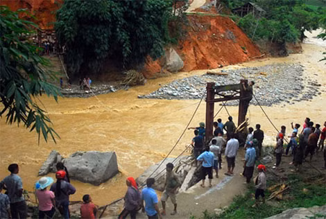 Bị cô lập và không thể liên lạc do không có điện và sóng điện thoại, giới chức và người dân đã nối dây ròng rọc hai đầu cầu để tiếp tế nhu yếu phẩm cho người dân. Ảnh: Báo Lào Cai.