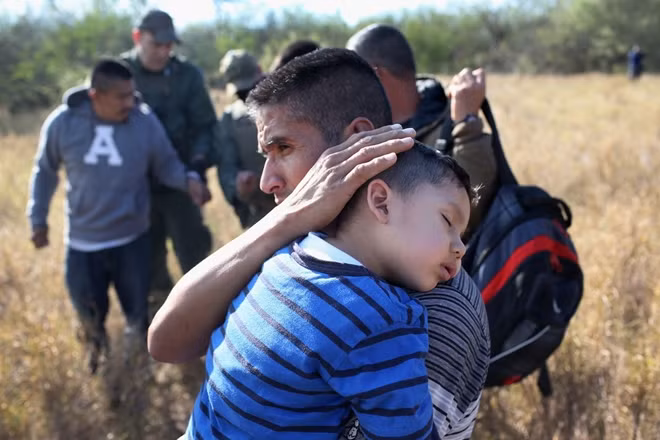 Một em bé được cha bế ở gần biên giới Mỹ - Mexico. Ảnh: Politico