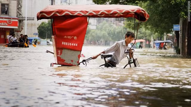 Một người đàn ông cố gắng kéo chiếc xe chở khách du lịch ra khỏi tuyến đường bị ngập nước. Theo Reuters, giới chức Trung Quốc cảnh báo rằng người dân không nên chủ quan bởi cả các địa điểm có địa hình cao như khu Nội mông cũng có nguy cơ bị ngập.