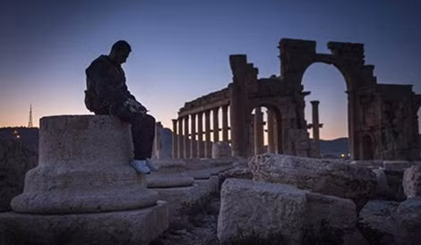 Một người lính Syria ngồi lặng lẽ giữa đống đổ nát ở Palmyra.