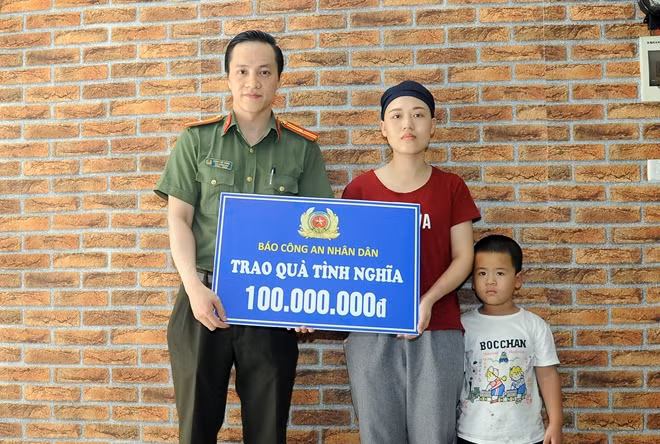 Thiếu tá Đặng Việt Hưng, Phó Trưởng Ban Thời sự - Chính trị, Báo CAND trao số tiền 100 triệu đồng cho Thượng úy Trần Ngọc Yến.