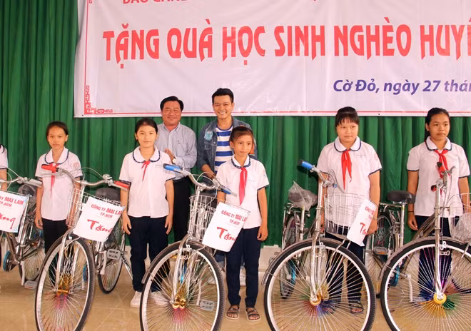 Diễn viên Linh Tý (áo khoác) cùng chính quyền địa phương tặng xe cho học sinh khó khăn.