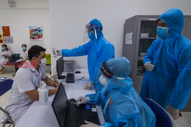 Nhân viên y tế tư vấn, hướng dẫn, đo thân nhiệt của người được tiêm.