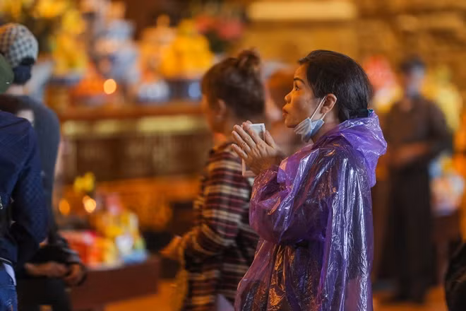 Người dân mặc áo mưa vào điện thắp hương là một hình ảnh hay xuất hiện trong ngày hôm nay ở đây.