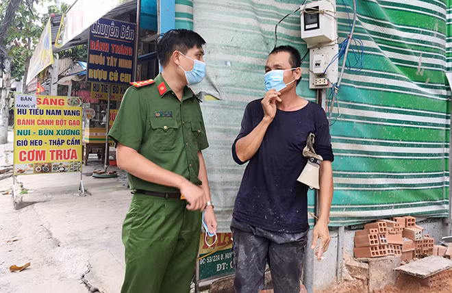 Đại úy Nguyễn Quốc Thái nhắc nhở và tặng khẩu trang cho người dân.