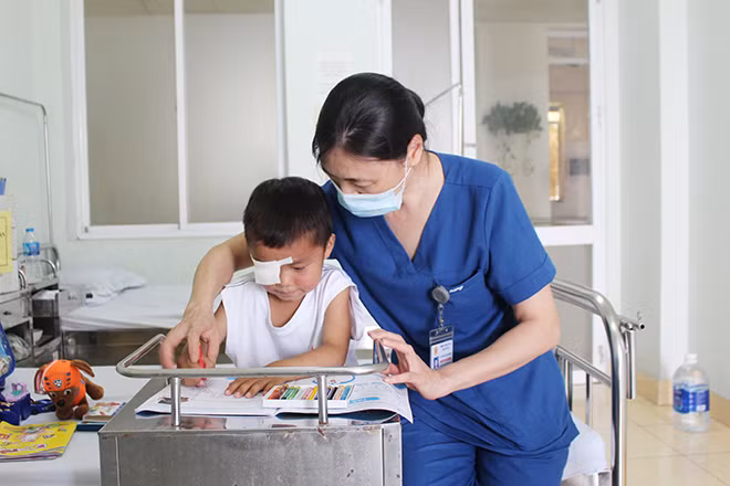Điều dưỡng trưởng Nguyễn Thị Hương hướng dẫn bé Dia tô chữ.