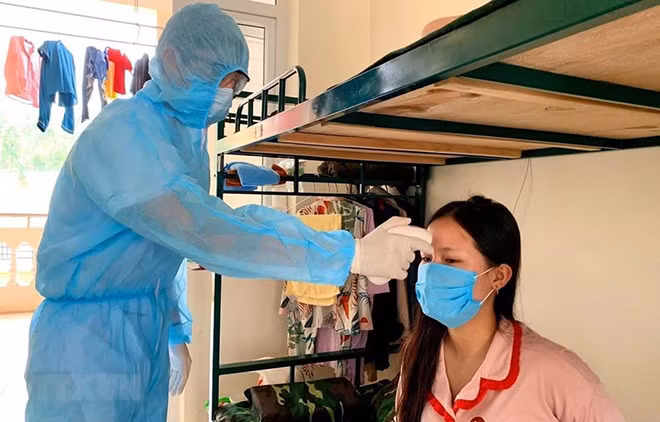 Đo thân nhiệt cho người dân trong khu cách ly. (Ảnh minh hoạ: TTXVN )