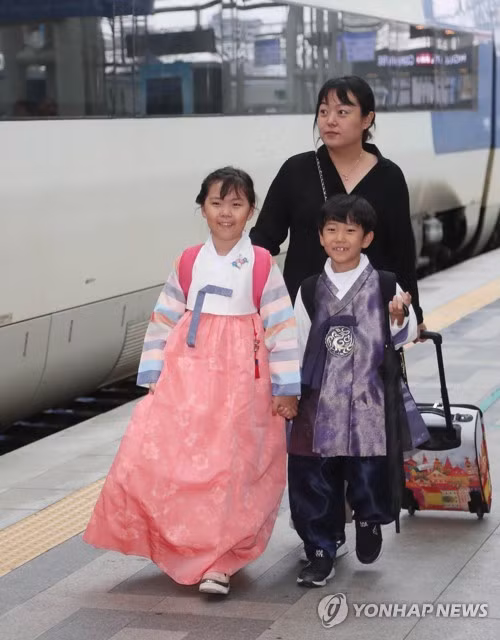 Người Hàn Quốc gọi Tết Trung thu là Chuseok, đây là dịp để các thành viên gia đình tụ họp cảm ơn và tưởng nhớ tổ tiên. Kỳ nghỉ lễ năm nay của người Hàn kéo dài 3 ngày, tính từ ngày 22-9. Trong ảnh là hai chị em rạng rỡ trong bộ trang phục truyền thống Hanbok cùng mẹ xách vali về quê tại Nhà ga Seoul hôm 21-9.