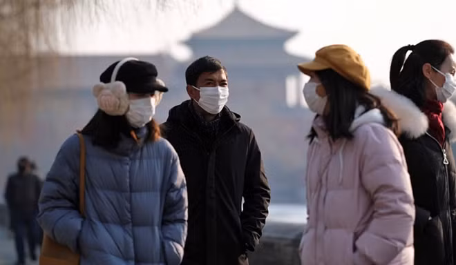 Người dân Bắc Kinh đeo khẩu trang khi đi qua khu vực Tử Cẩm Thành. (Ảnh: Reuters)