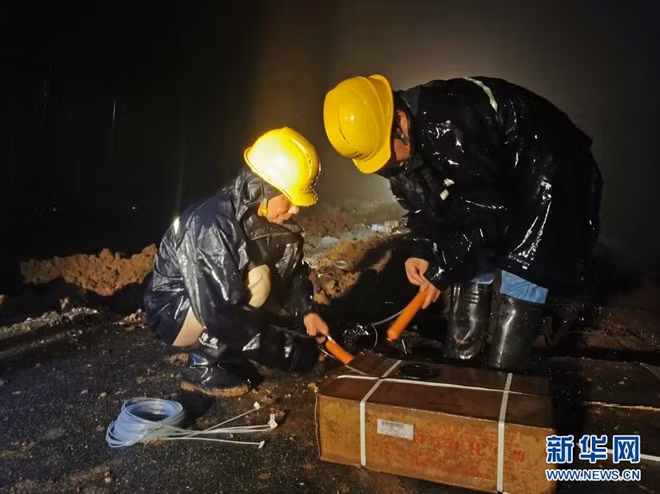 Nhân viên chuẩn bị thuốc nổ để tiến hành phá đê ngay trong đêm. (Ảnh: Tân Hoa Xã)