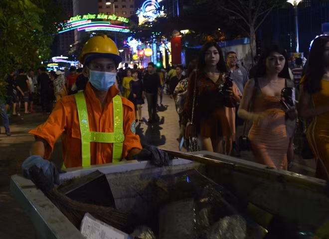 Công nhân vệ sinh liên tục thu gom rác trên đường hoa Nguyễn Huệ bởi dòng người đổ về đây quá lớn.