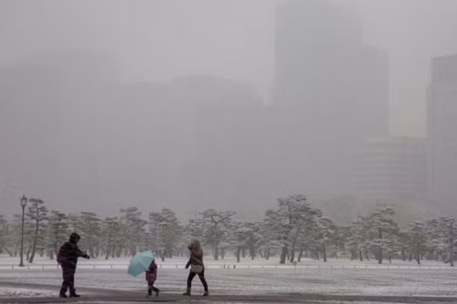 Một gia đình đang cố gắng di chuyển trong màn tuyết rơi dày đặc. Ảnh: EPA