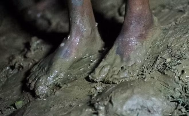 Đôi bàn chân lấm bùn của một em nhỏ đang cố gắng vượt biên trong đêm.