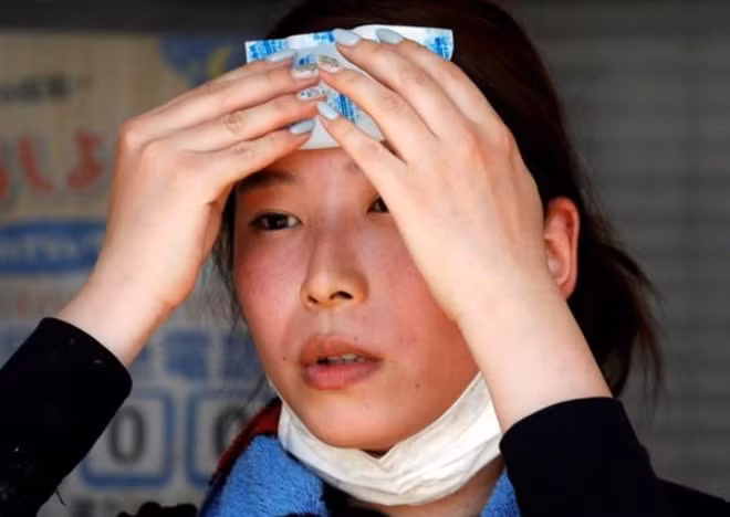 Một người phụ nữ chườm túi đá lạnh để giảm nhiệt. Ảnh: Reuters