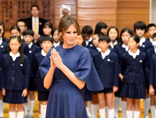 Ngày 6-11, Đệ nhất phu nhân Melania Trump đến thăm một trường học với phu nhân Akie Abe. Khoảng 300 học sinh Nhật Bản đã chào đón hai vị phu nhân bằng một bài hát của trường. Bà Melania Trump đã chọn một chiếc váy xanh thanh lịch cùng tông với chiếc váy mà phu nhân thủ tướng Shino Abe mặc và trùng màu với màu đồng phục của trường tiểu học Kyobashi Tsukiji, tạo nên một sự gần gũi với các em học sinh nơi đây. Ảnh: Reuters