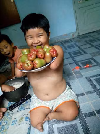 Bé Hoài Thương khoe tự mình bê được đĩa hoa quả.