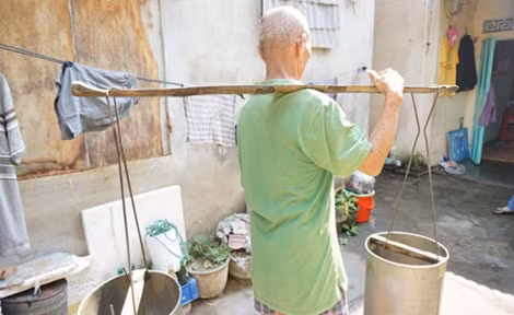 Ông Đường đã 82 tuổi nhưng vẫn miệt mài gánh nước mưu sinh.