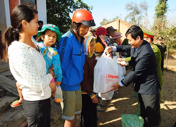 Đại diện chính quyền địa huyện, Công an huyện và chính quyền xã trao quà Tết cho người dân.