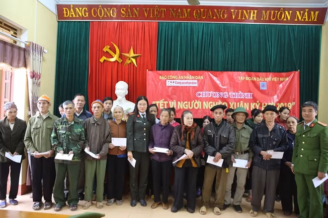 Thiếu tá Cao Thị Hồng, Phó trưởng Ban Kinh tế - Pháp luật, Báo CAND cùng đại diện Công an huyện Trấn Yên trao quà Tết tới đồng bào nghèo xã Lương Thịnh.