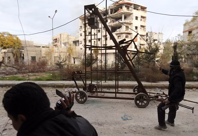 Máy ném lựu đạn tự chế của lực lượng Quân đội Syria Tự do (FSA). Loại vũ khí này có cơ cấu hoạt động như máy ném đá thời trung cổ, khi một khối nặng treo cao được hạ xuống nó sẽ kéo một sợi dây ném lựu đạn đi xa hơn cách ném thông thường. Ảnh: Reuters