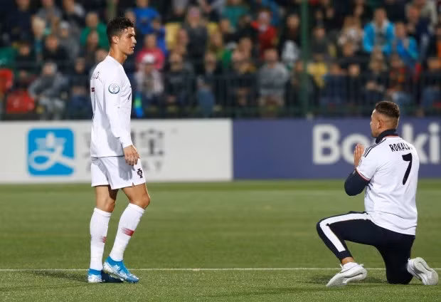 Một CĐV bất ngờ quỳ trước mặt Ronaldo trong trận đấu. Ảnh: Reuters.