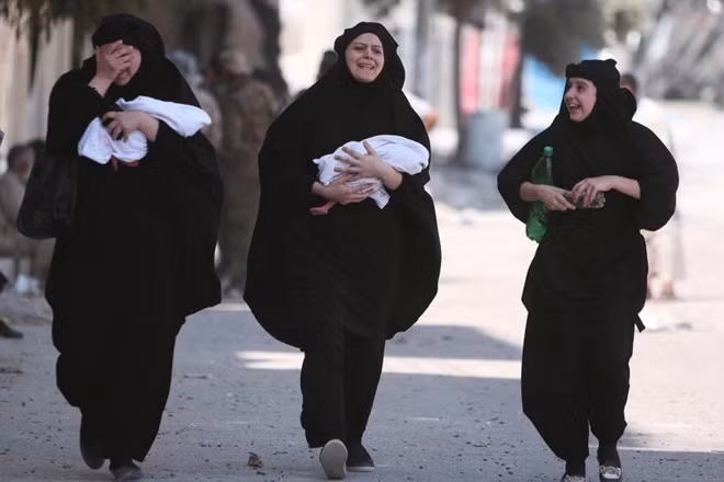 Hai phụ nữ Syria vừa khóc vừa bế con mới sinh bước trên đường phố quê hương để đón những tia nắng đầu tiên sau những ngày tăm tối