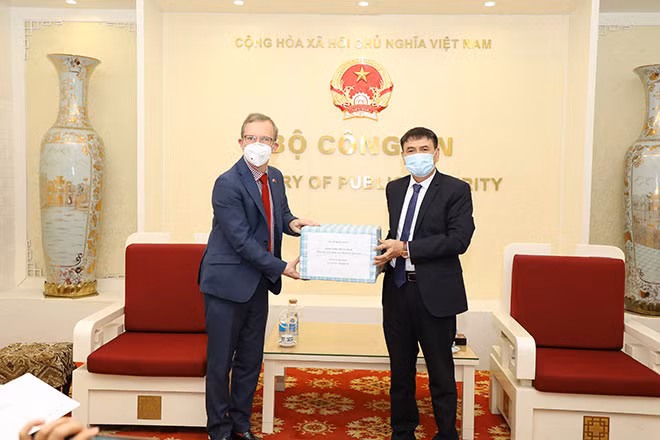 Trung tướng Trương Văn Thông, Cục trưởng Cục Đối ngoại trao khẩu trang của Bộ Công an Việt Nam gửi tặng các cơ quan thực thi pháp luật Anh cho Đại sứ Anh tại Việt Nam Gareth Ward.