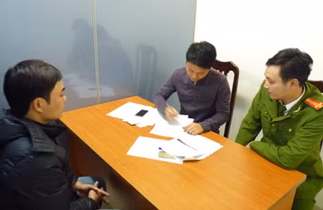 Đối tượng truy nã Phan Tuấn Anh (mặc áo đen bên trái ảnh) đang khai báo tại cơ quan Công an.