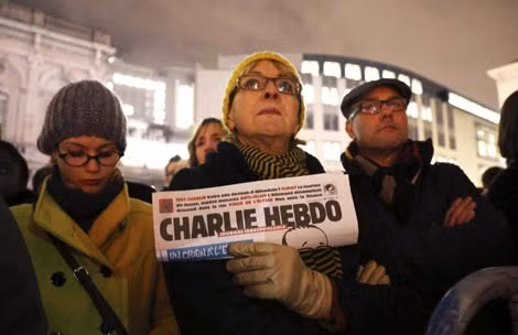 Một người phụ nữ cầm theo bản sao tờ báo Charlie Hebdo, trong buổi tưởng niệm cho các nạn nhân diễn ra bên ngoài trụ sở Nghị viện châu Âu ở Brussels.