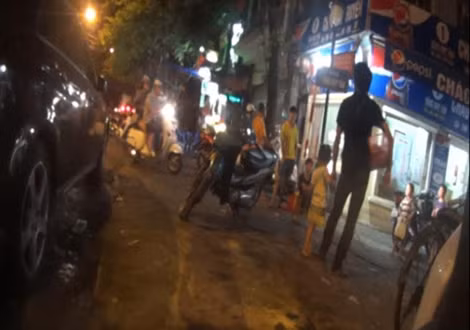 Trẻ nhỏ được người lớn dắt đi bán kẹo cao su trên đường phố Hà Nội.