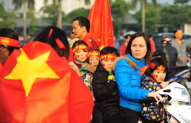 Một bà mẹ chở trẻ con đi cổ vũ bóng đá tại Mỹ Đình.