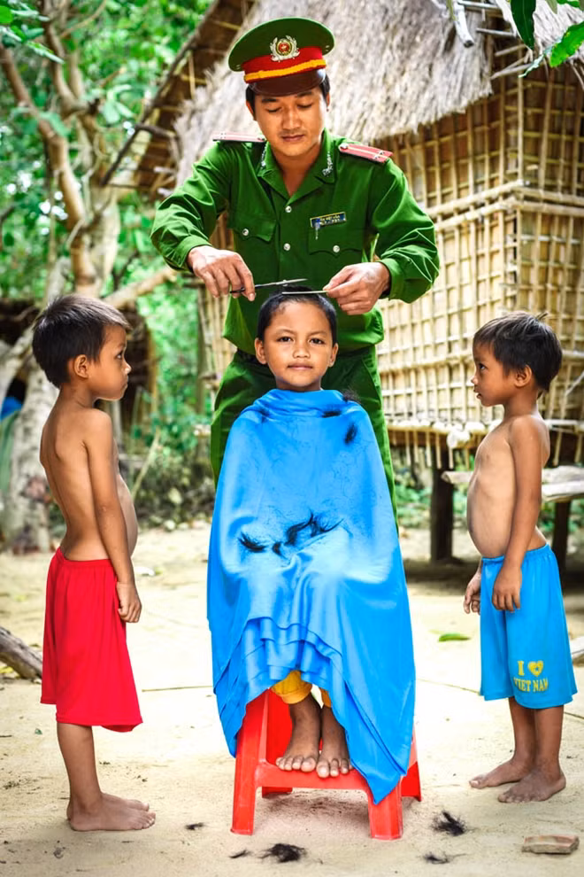 Hè về, Đoàn Thanh niên công an huyện Vĩnh Thạnh, tỉnh Bình Định đã có nhiều hoạt động tình nguyện giúp đồng bào dân tộc thiểu số. Trong ảnh, trung úy Trần Việt Hòa hớt tóc miễn phí cho trẻ em vùng cao. (Tác giả: Từ Ngọc Vũ - Bình Định).