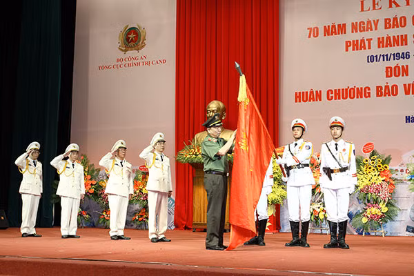 Thừa ủy quyền của Chủ tịch nước, Bộ trưởng Tô Lâm gắn Huân chương Bảo vệ Tổ quốc hạng nhất lên Cờ truyền thống của Báo CAND. Ảnh: T.Xuân.