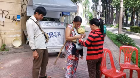 Một người mẹ bị mù lòa mưu sinh trên đường.