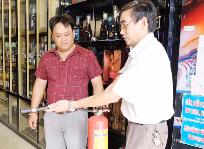 Ông Hùng hướng dẫn người dân sử dụng bình chữa cháy xách tay.