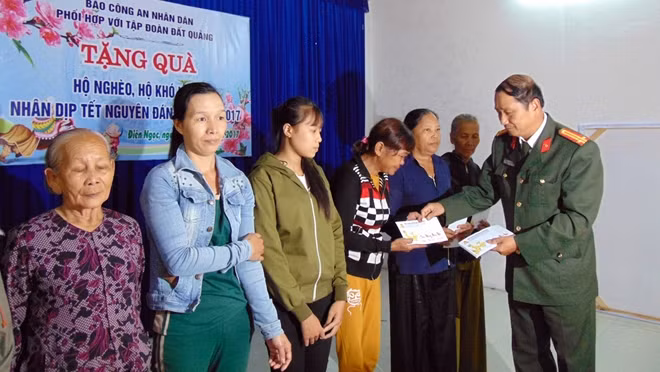 Trung tá Nguyễn Văn Long, Phó Trưởng ban thư ký tòa soạn, Trưởng Văn phòng Thường trú Báo CAND tại miền Trung, trao quà cho người dân.