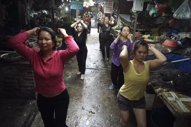 Vào 14h chiều, một nhóm khác lại bắt đầu buổi tập Aerobic tại khu vực bán rau củ quả. Nhóm này do chị Dương Thị Dung (người áo đỏ) khởi xướng. Năm nay chị Dung đã 57 tuổi. Chị chia sẻ, cứ mỗi khi gần đến giờ tập là thấy háo hức, tinh thần cũng vì thế rất vui.